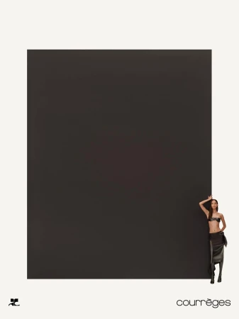 Model standing against a massive dark rectangular panel in a minimal white studio setting for Courreges Fall 2024 ad campaign