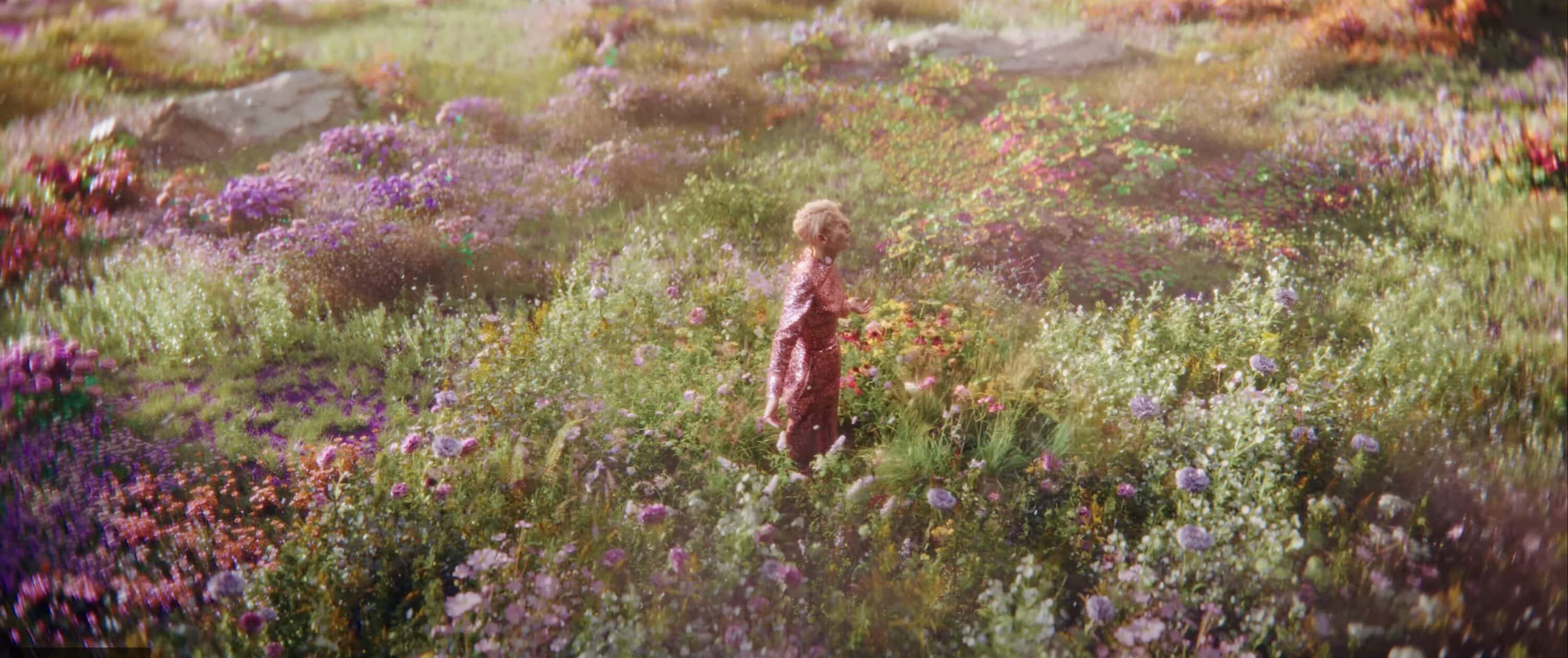 Tilda Swinton standing amidst a vibrant wildflower field for the Delpozo Obertura Fall 2024 campaign