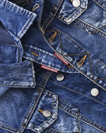 Close-up of blue distressed denim fabric with metal buttons and red Dsquared2 labels