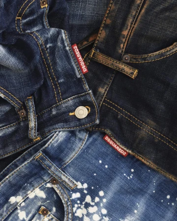 Close-up of layered denim jeans featuring contrasting washes, distressed textures, and visible Dsquared2 branded red labels.