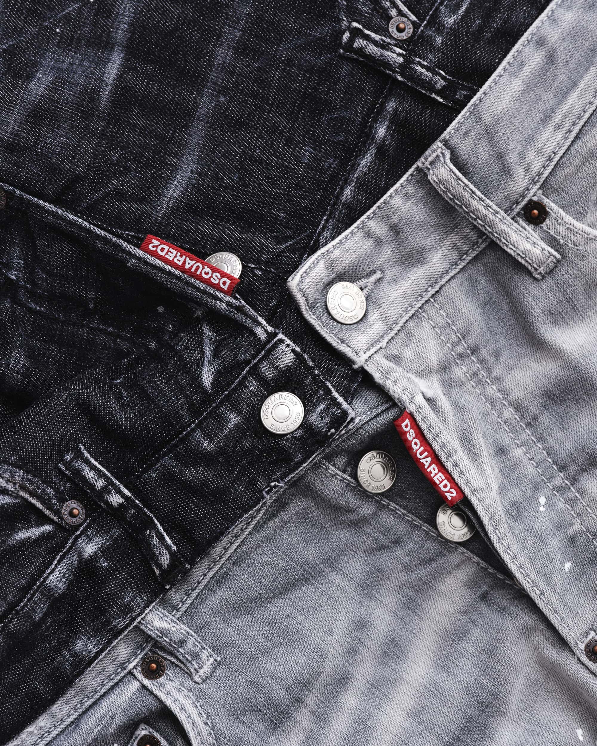 Close up of layered dark grey and black denim jeans with red Dsquared2 tags and metal buttons from the Fall 2024 ad campaign.