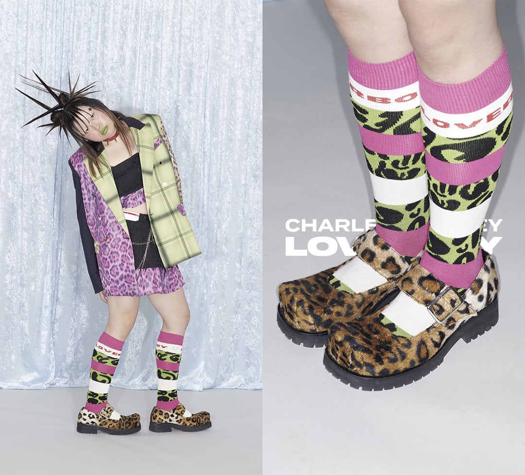 Model wearing patterned blazer, leopard print mini skirt, and furry platform shoes with printed socks against a light blue backdrop.