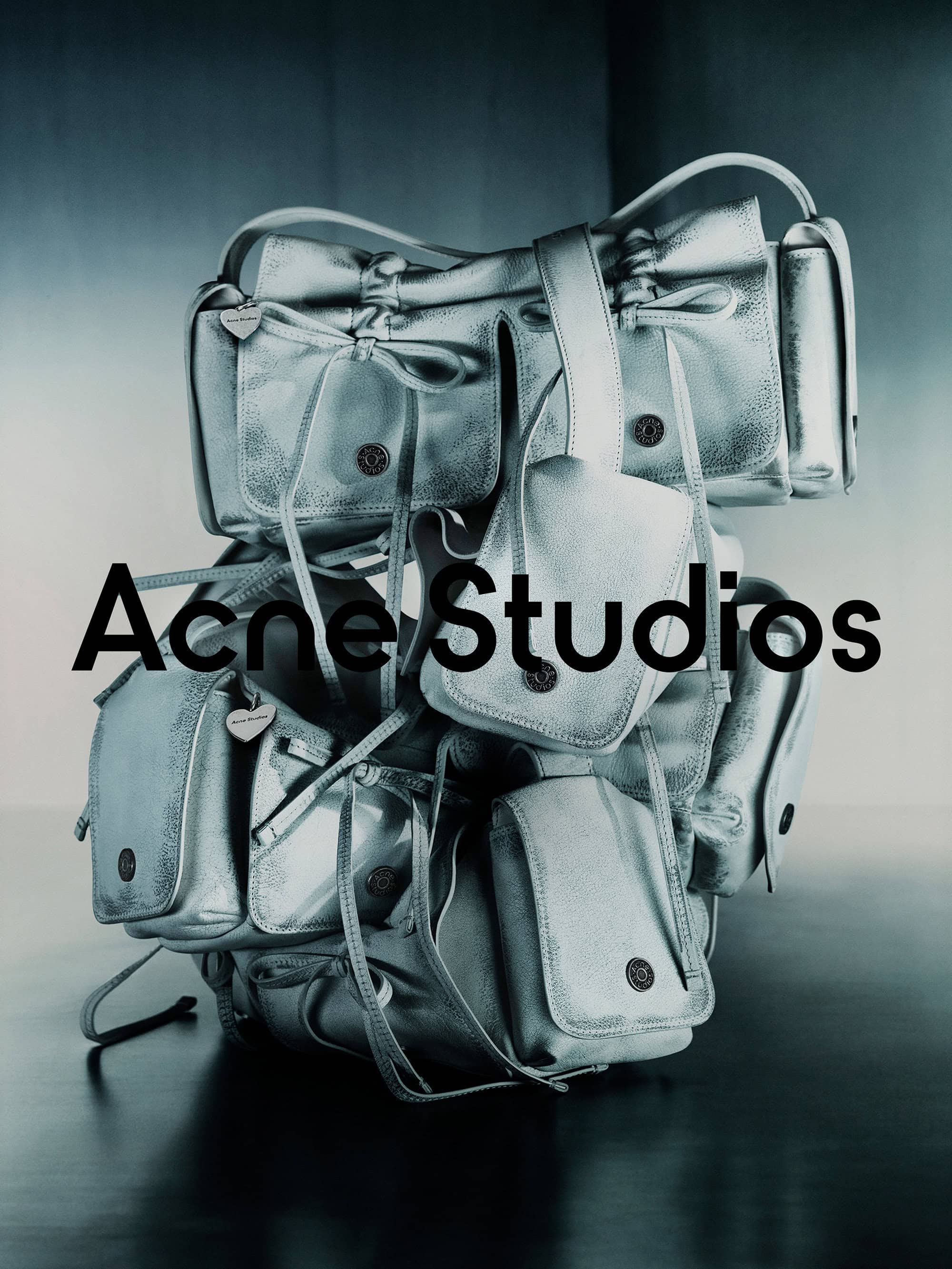 A towering stack of metallic silver leather shoulder bags against a dark gradient studio background with bold typography