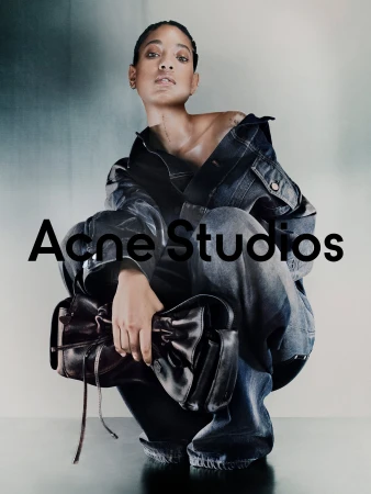 Willow Smith crouching in a dark denim jacket and jeans, holding a black leather handbag against a gradient backdrop