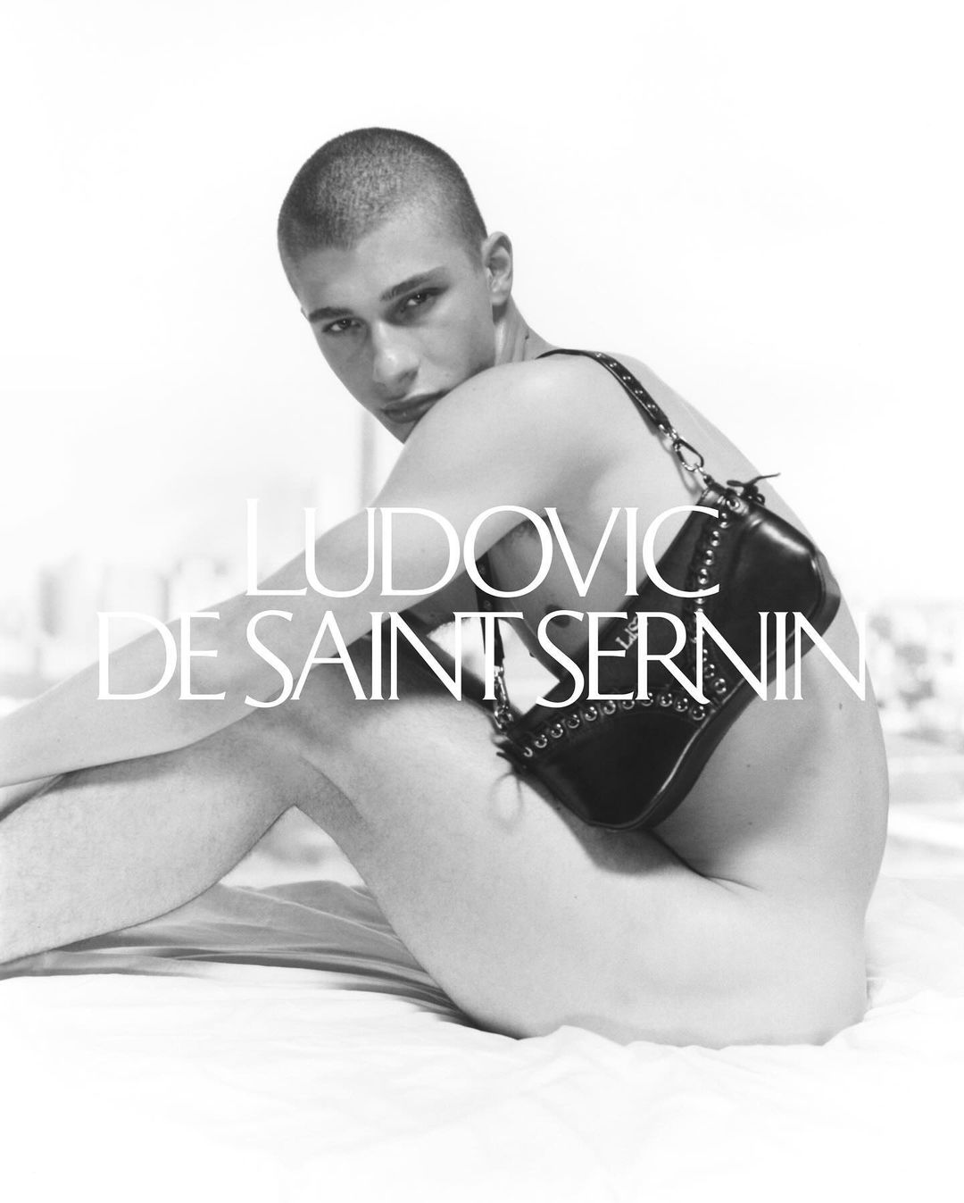 Model with a buzzed head posing with a black leather Cleavage Bag for Ludovic de Saint Sernin