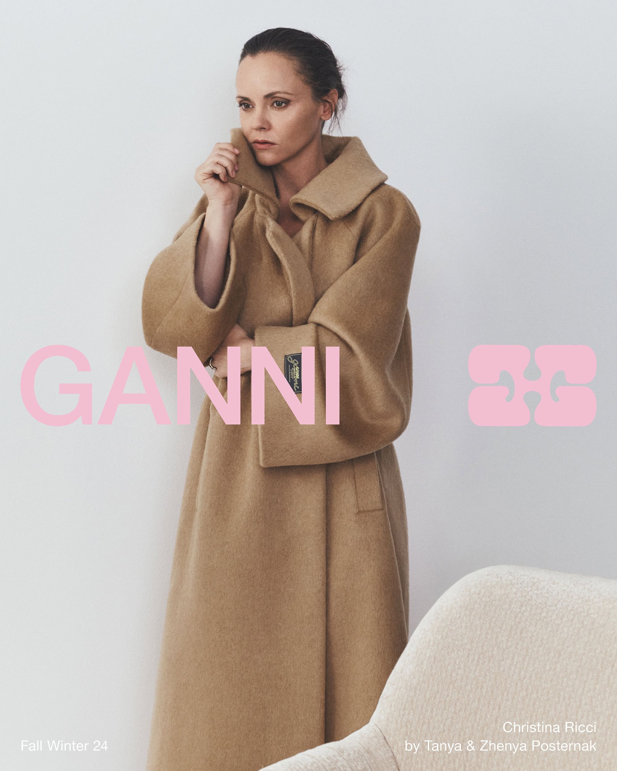Christina Ricci wearing a long camel coat against a plain white background for Ganni Fall 2024 ad campaign