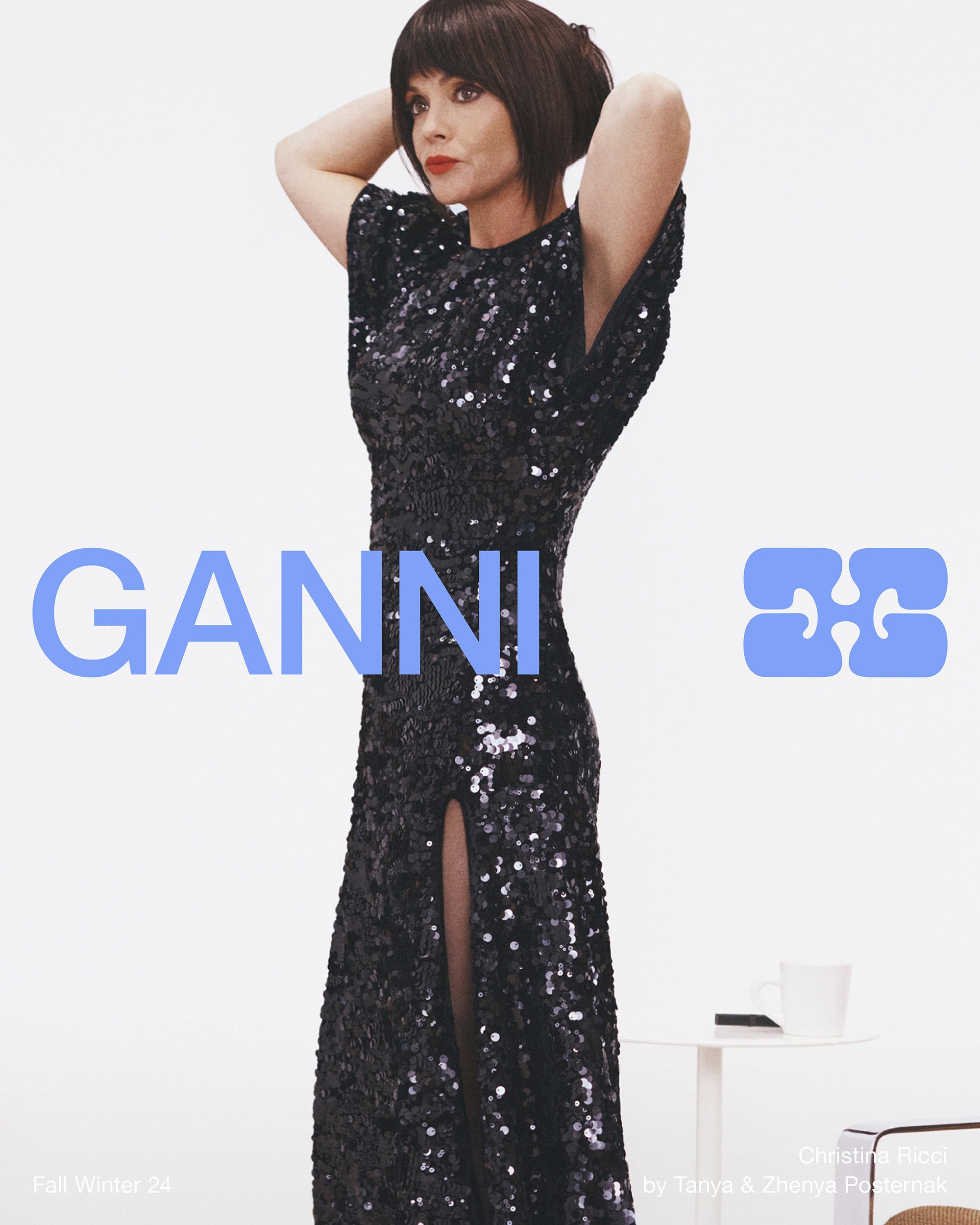 Christina Ricci in a black sequin dress with her hands behind her head against a white background for Ganni Fall 2024 ad campaign.