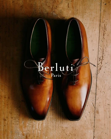 Top-down view of a pair of polished brown leather dress shoes on a wooden surface for Berluti Fall 2024 campaign