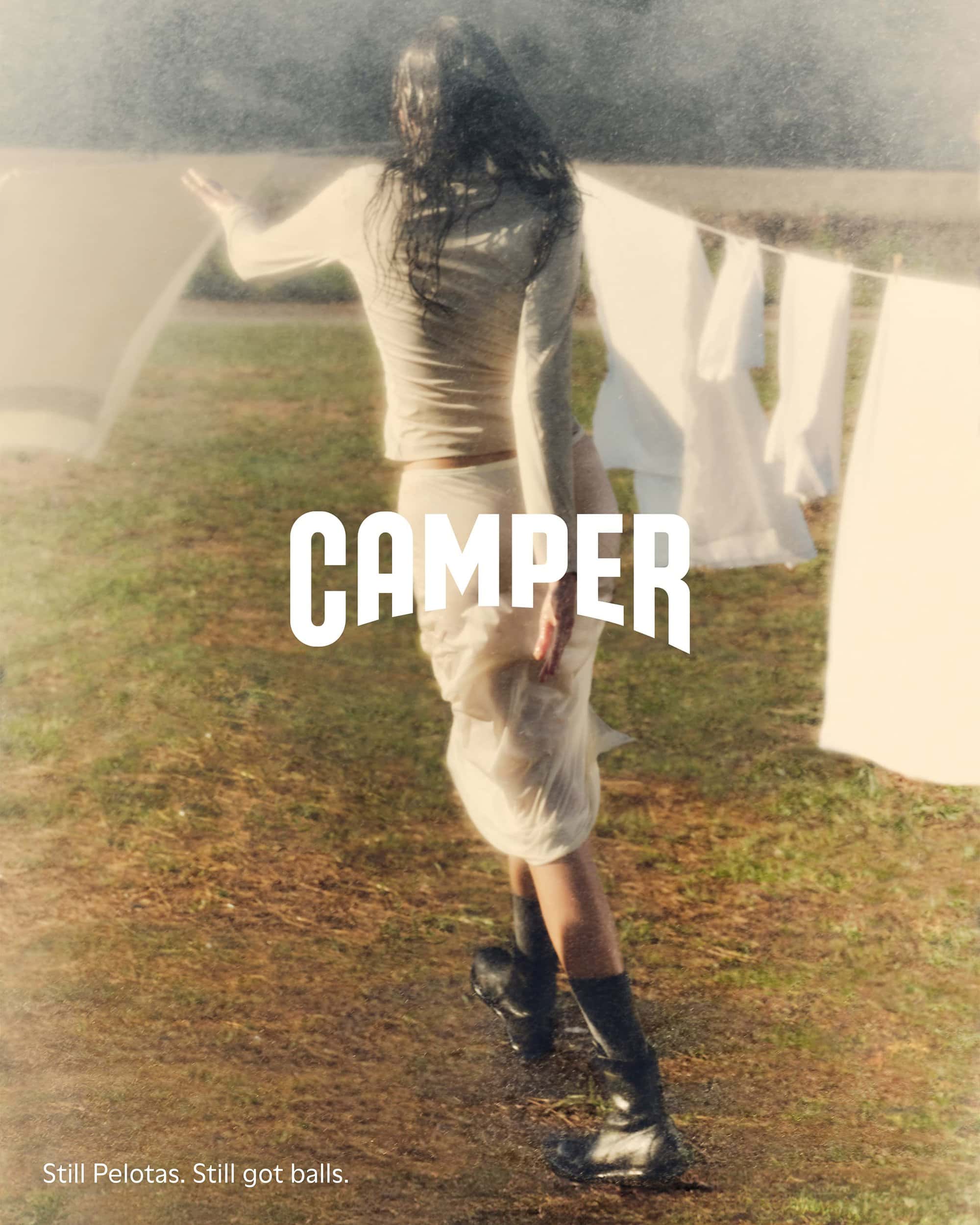 Woman in white top walking outdoors past a clothesline with white laundry for Camper ad campaign
