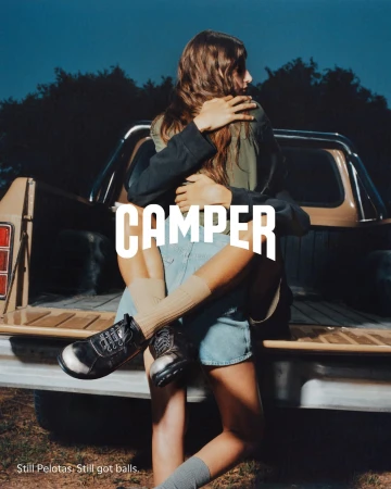 Two people embracing in front of a pickup truck wearing casual apparel and footwear
