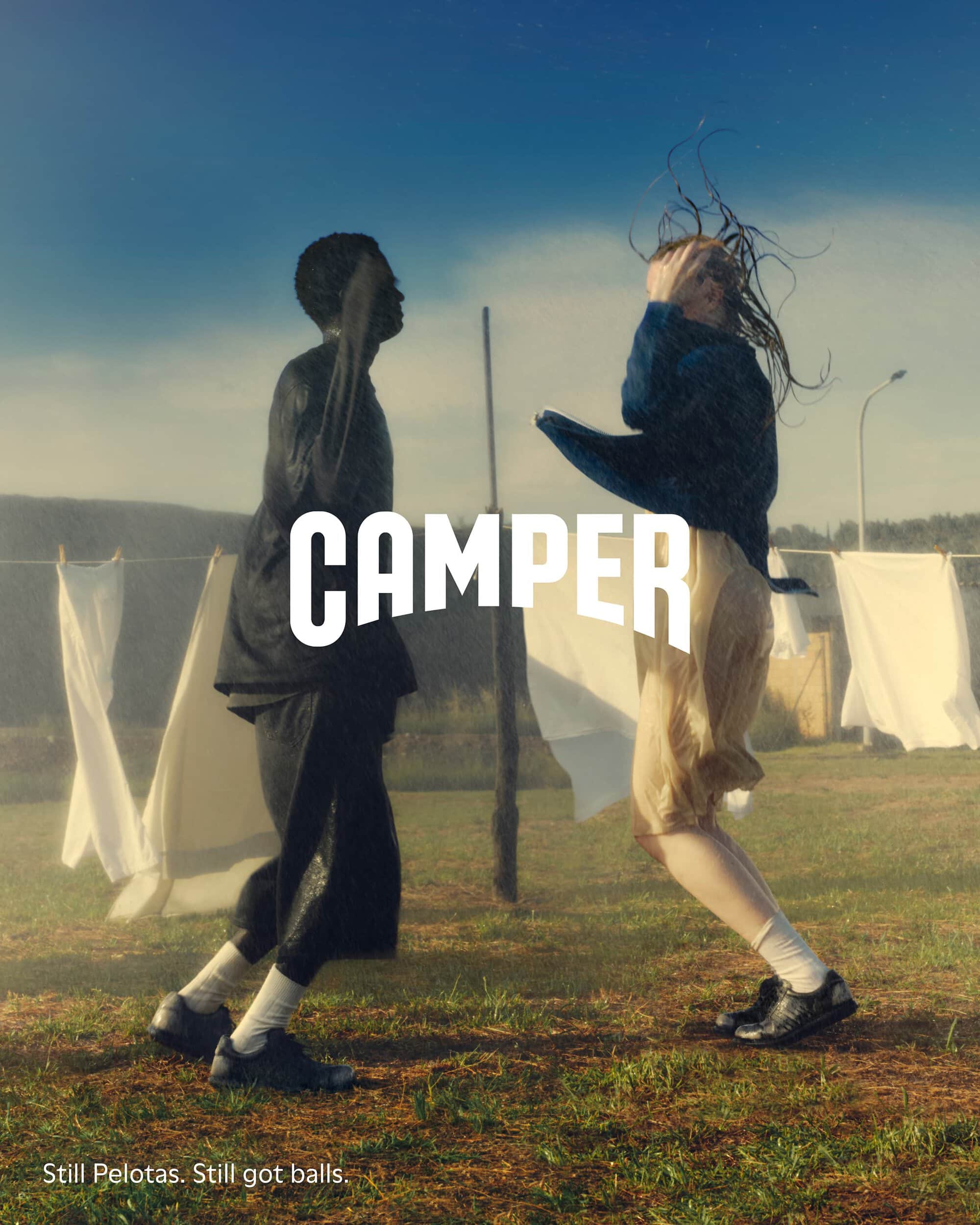 Two models outdoors jumping on grass in a campaign image for Camper, featuring clothing and footwear against a clothesline and sky.