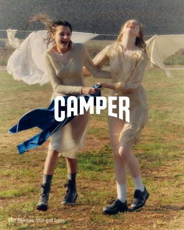 Two women laughing and playing outdoors in the rain near a clothesline for Camper Fall 2024 ad campaign