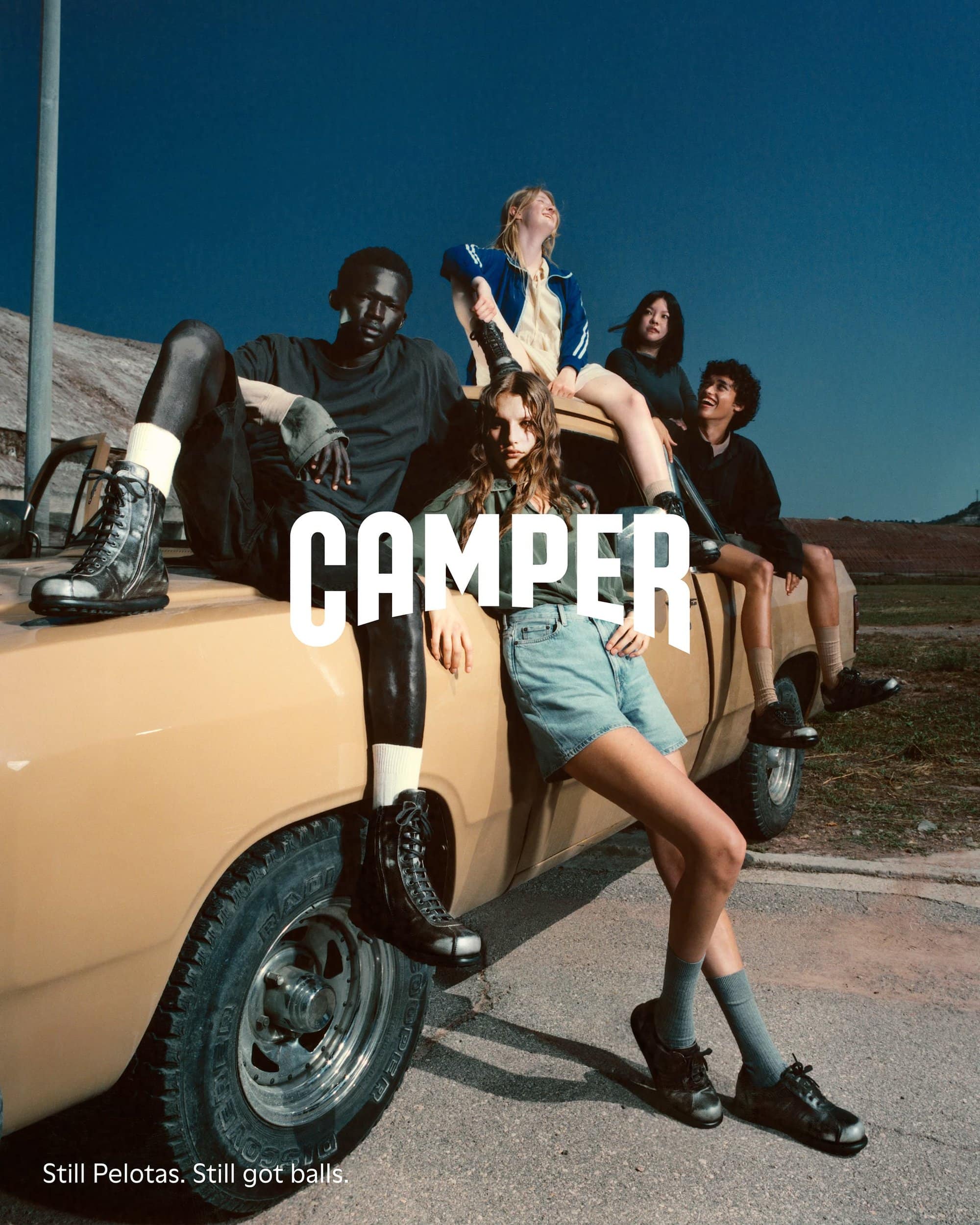 Five models posing on a vintage beige pickup truck against a clear blue sky for Camper Fall 2024 ad campaign.