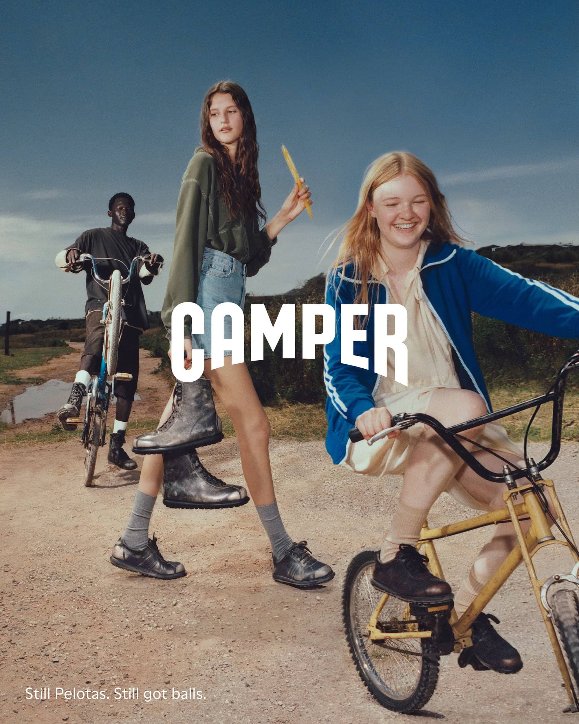 Three models outdoors on bicycles and walking along a dirt road wearing Camper footwear for a fall campaign.