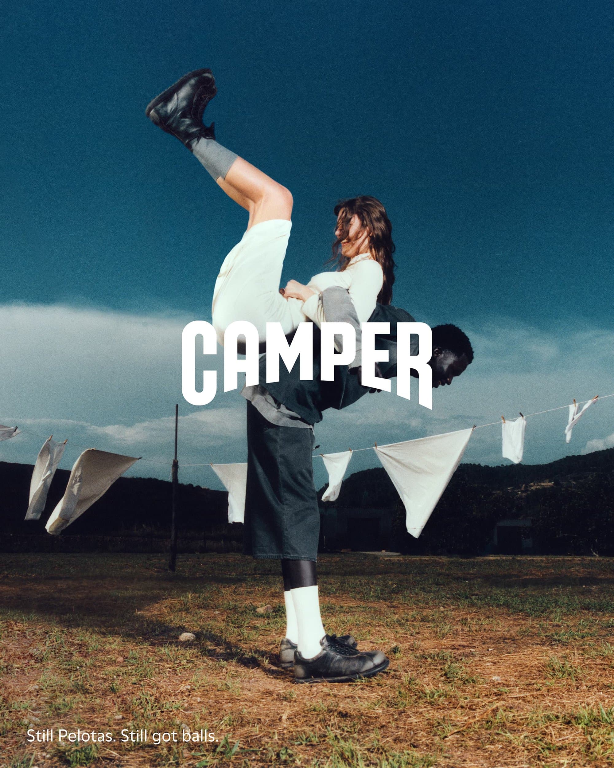 Man carrying a woman upside down outdoors against a blue sky, for the Camper Fall 2024 campaign