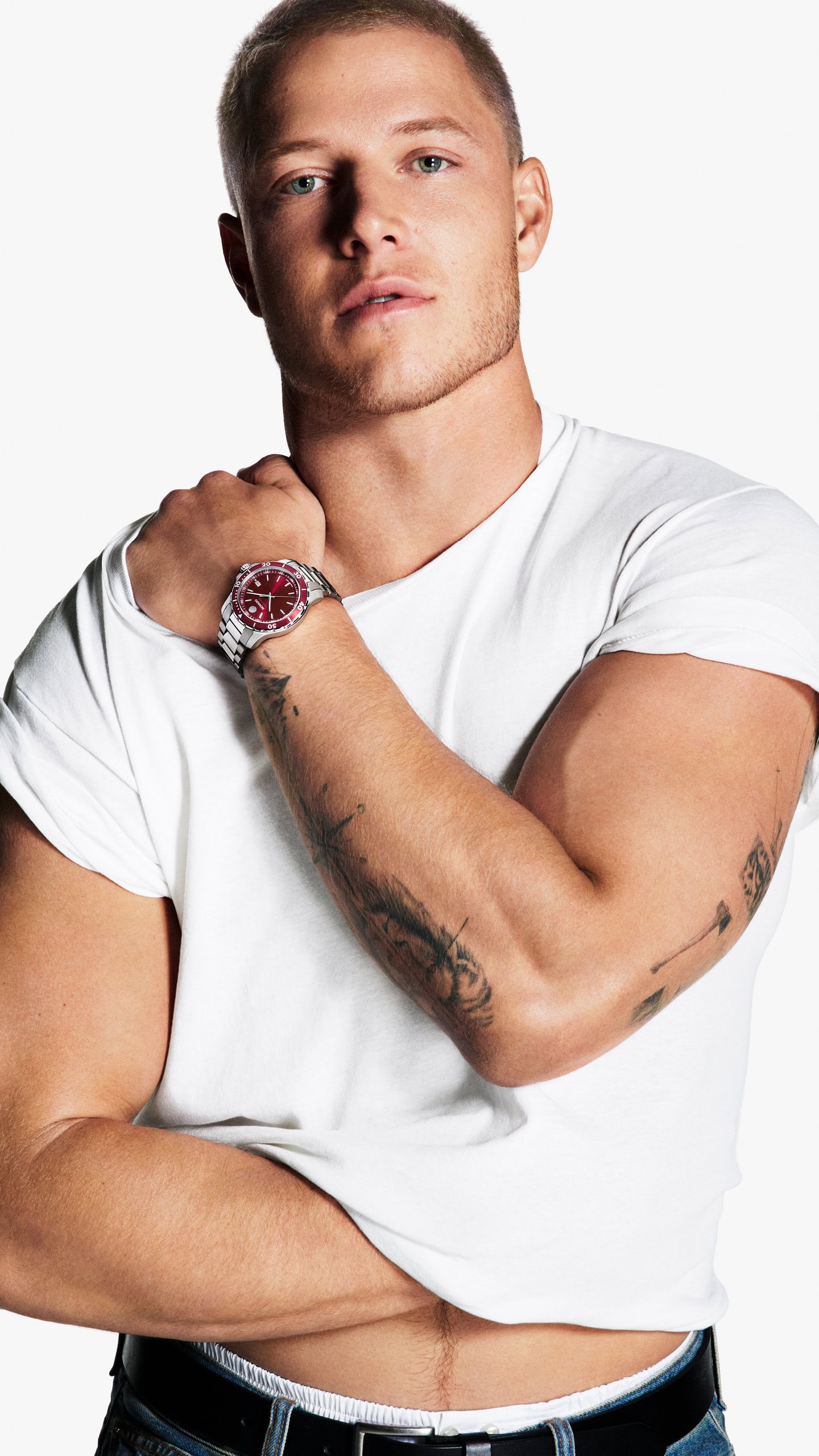 Christian McCaffrey wearing a white t-shirt and a luxury wristwatch against a solid white background for the Movado campaign.