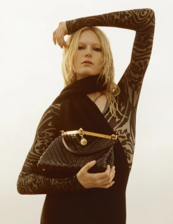 Model with blonde hair wearing patterned sleeves and holding a black woven handbag for Etro Fall 2024 ad campaign