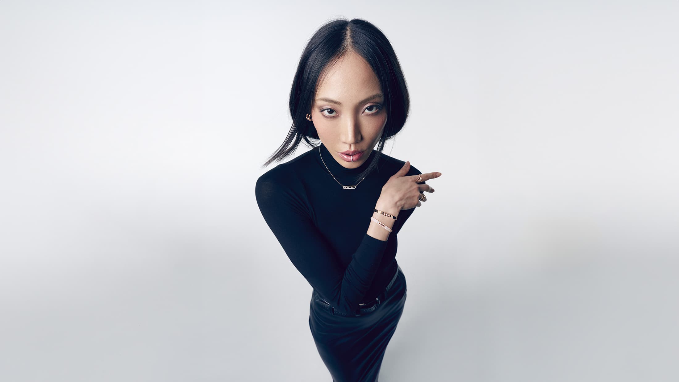 Model Soo Joo Park wearing black turtleneck and jewellery against a clean white backdrop for Messika Fall 2024 campaign
