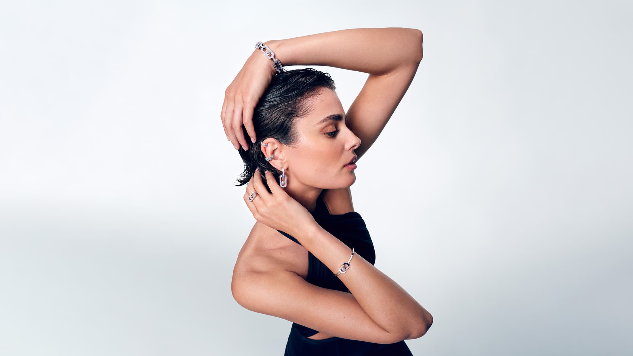 Taylor Hill wearing diamond jewelry and black dress against white backdrop for Messika Fall 2024 campaign