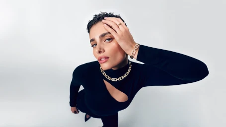 Model Taylor Hill wearing gold diamond jewellery and a black top against a white background for Messika