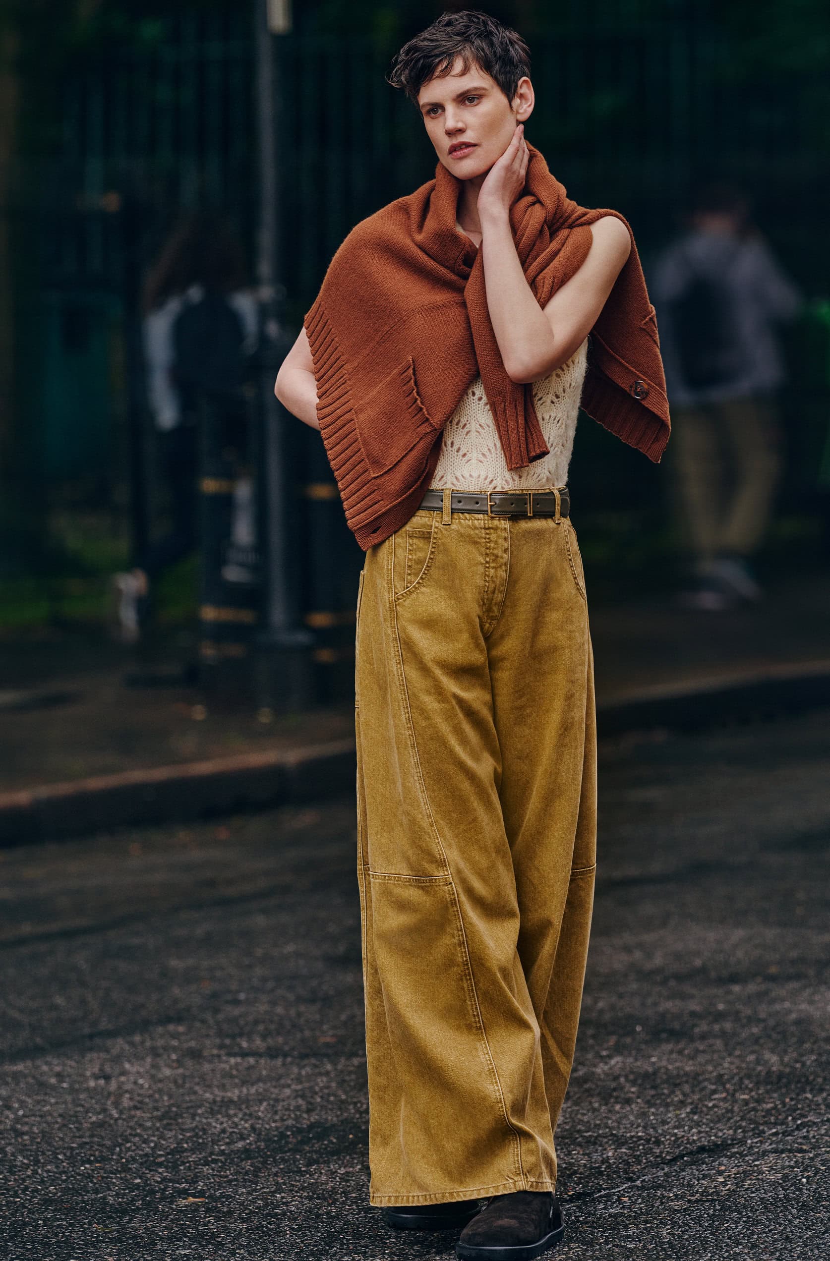 Model Saskia de Brauw in a brown sweater and wide yellow trousers outdoors on a street for ME+EM