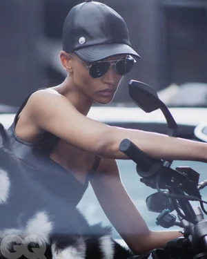Model Georgia Palmer wearing a black leather cap and sunglasses seated on a motorcycle for GQ Germany
