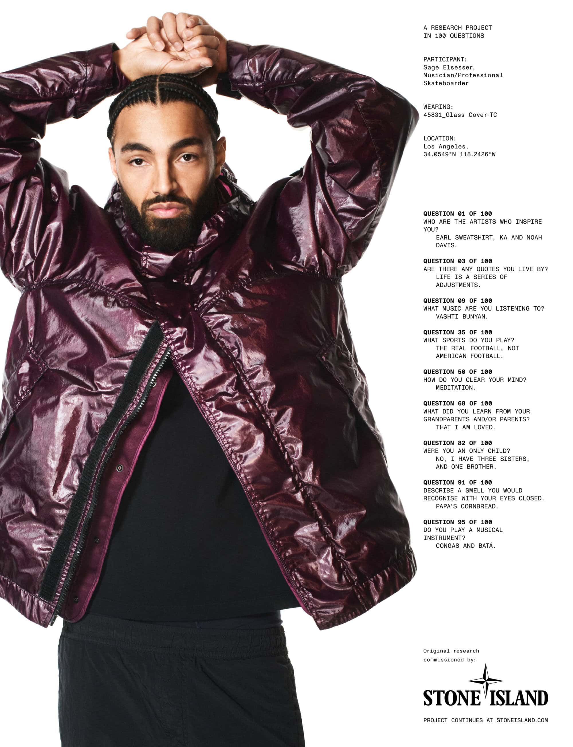 Man with braided hair and beard wearing a glossy dark purple hooded jacket against a white background