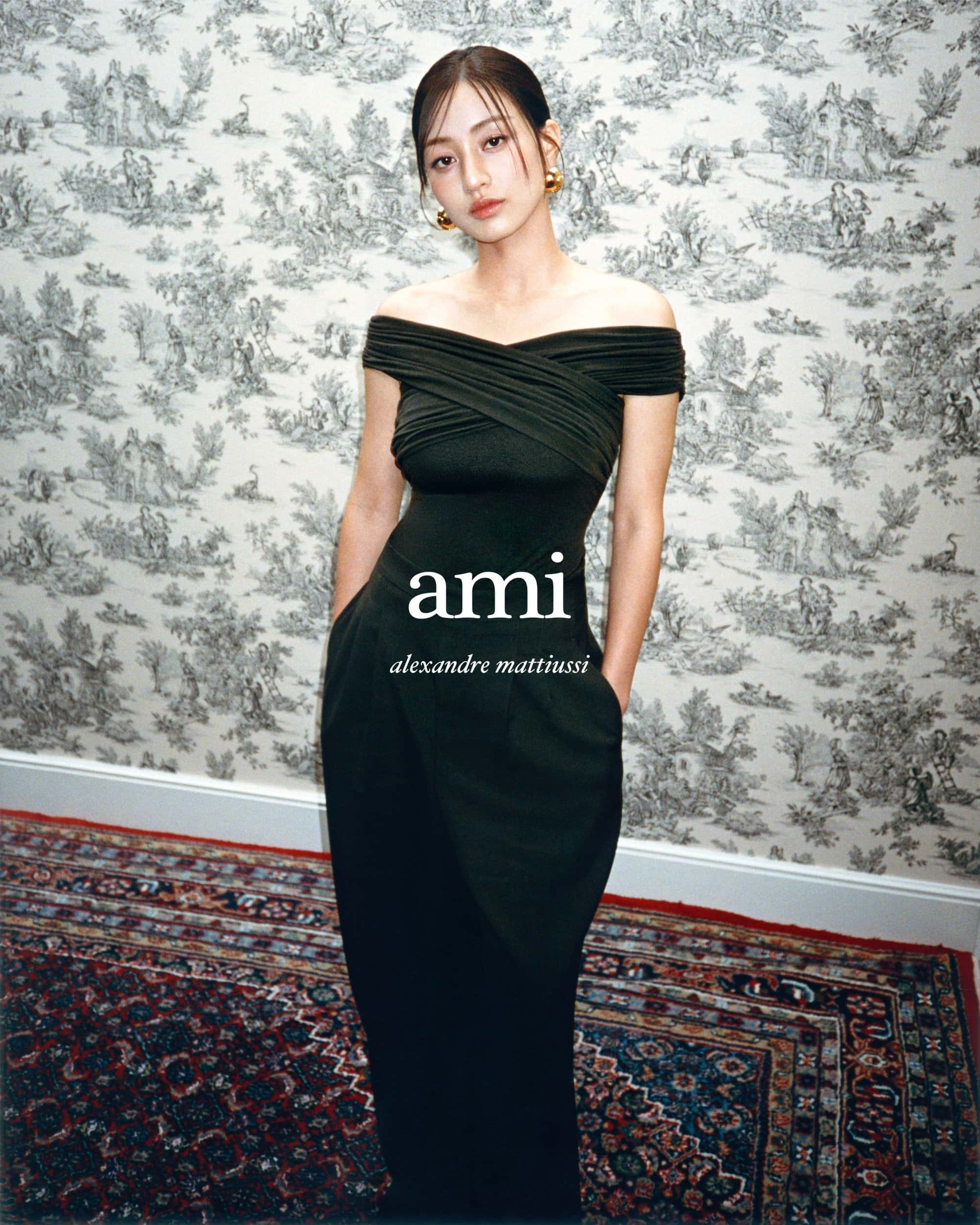 Model Jihyo wearing an off-shoulder black gown against a toile wallpaper background for Ami Fall 2024 ad campaign.
