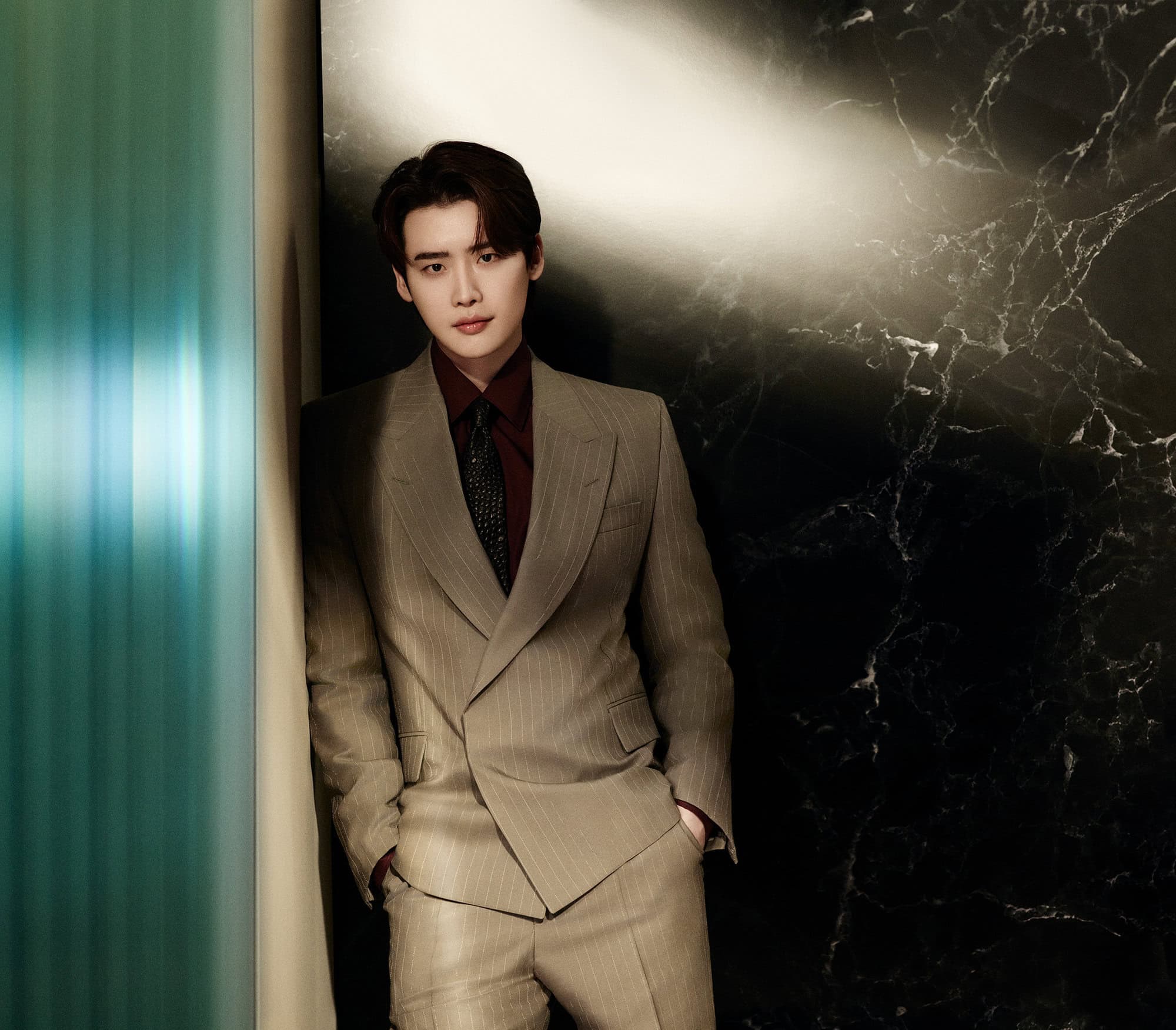 Lee Jong-suk wearing a taupe pinstripe suit and dark shirt for the BOSS Fall 2024 campaign, photographed by Mikael Jansson.