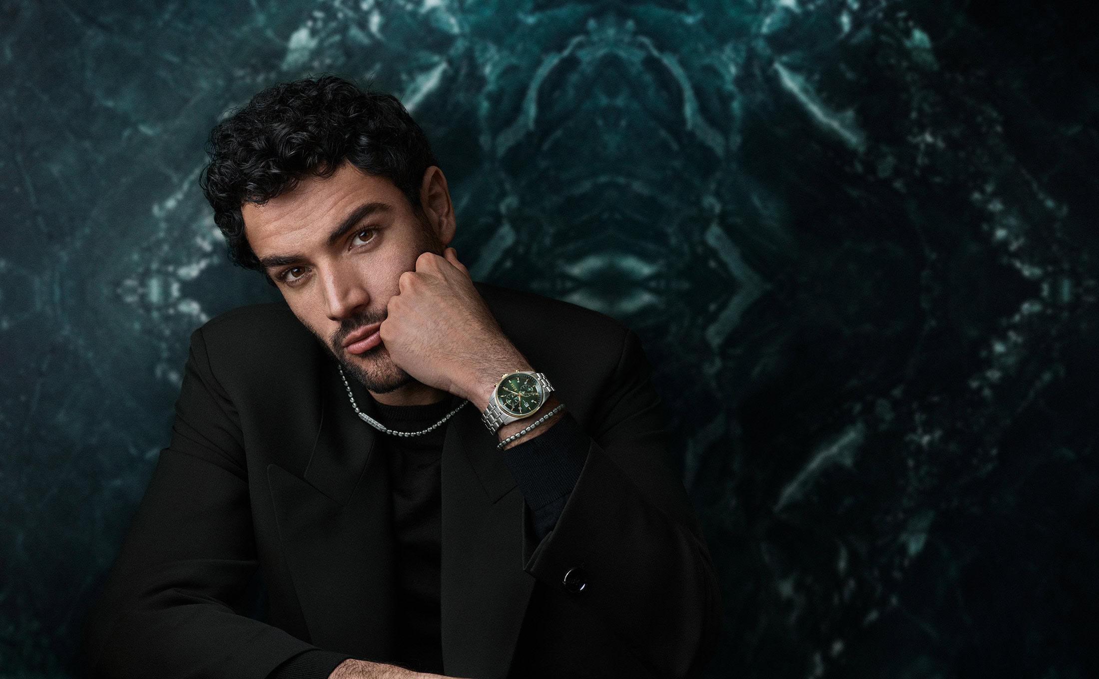 Matteo Berrettini wearing a black jacket and wrist watch against a dark green marble textured background for BOSS.