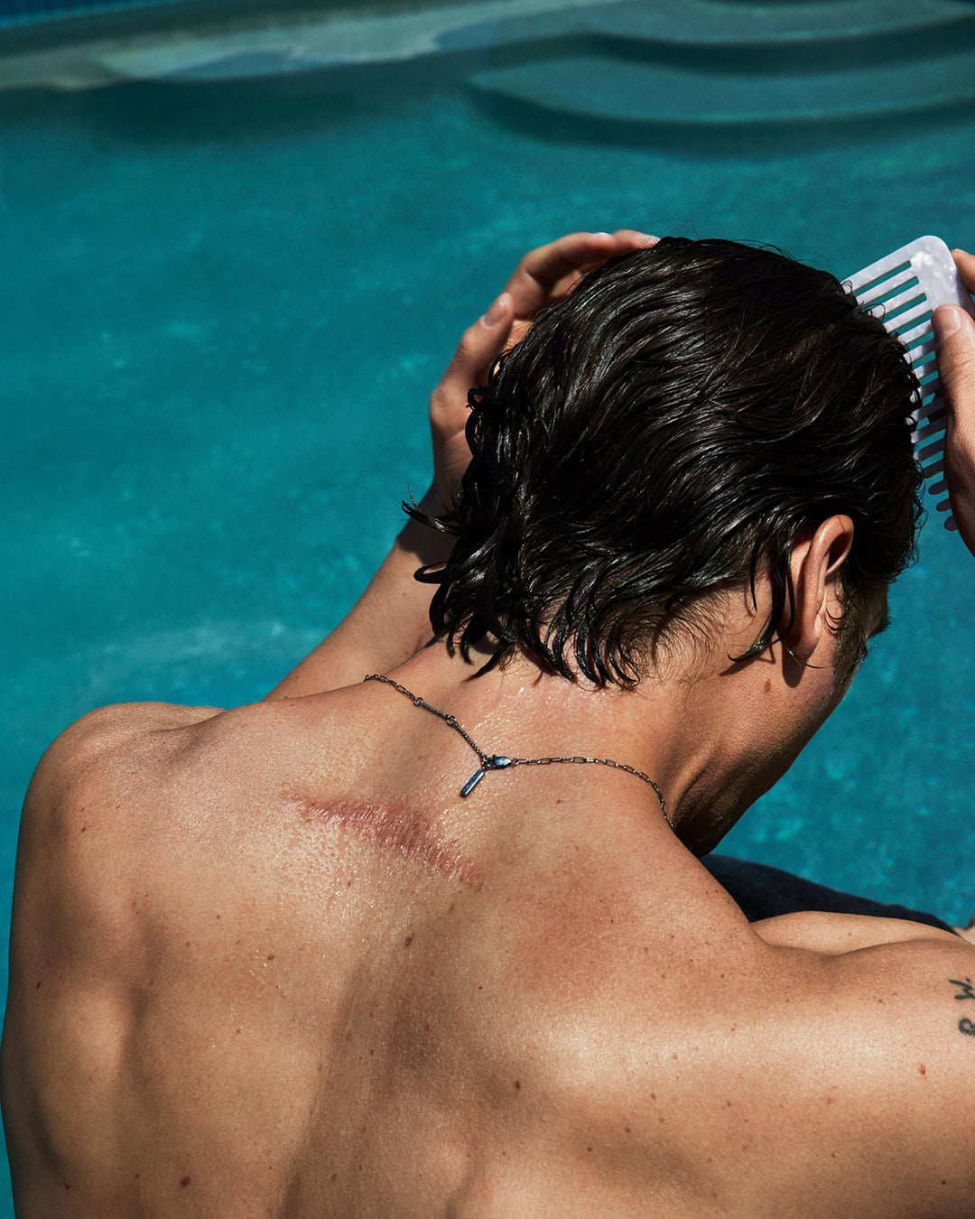 Jeremy Allen White combing his wet dark hair by an outdoor swimming pool for Calvin Klein Fall 2024 campaign