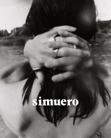 Close-up of hands clasped behind dark hair wearing silver rings against an outdoor water background with Simuero text overlay.