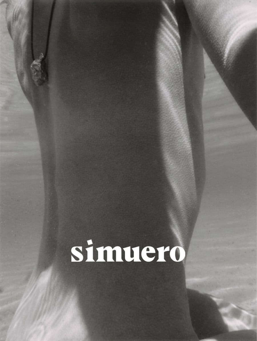 Monochrome underwater close-up of a person wearing a cord necklace with a pendant for Simuero