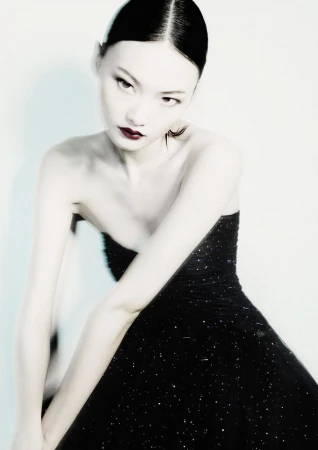 Model in a black strapless gown with dark lipstick against a pale background for Giorgio Armani Fall 2024 campaign