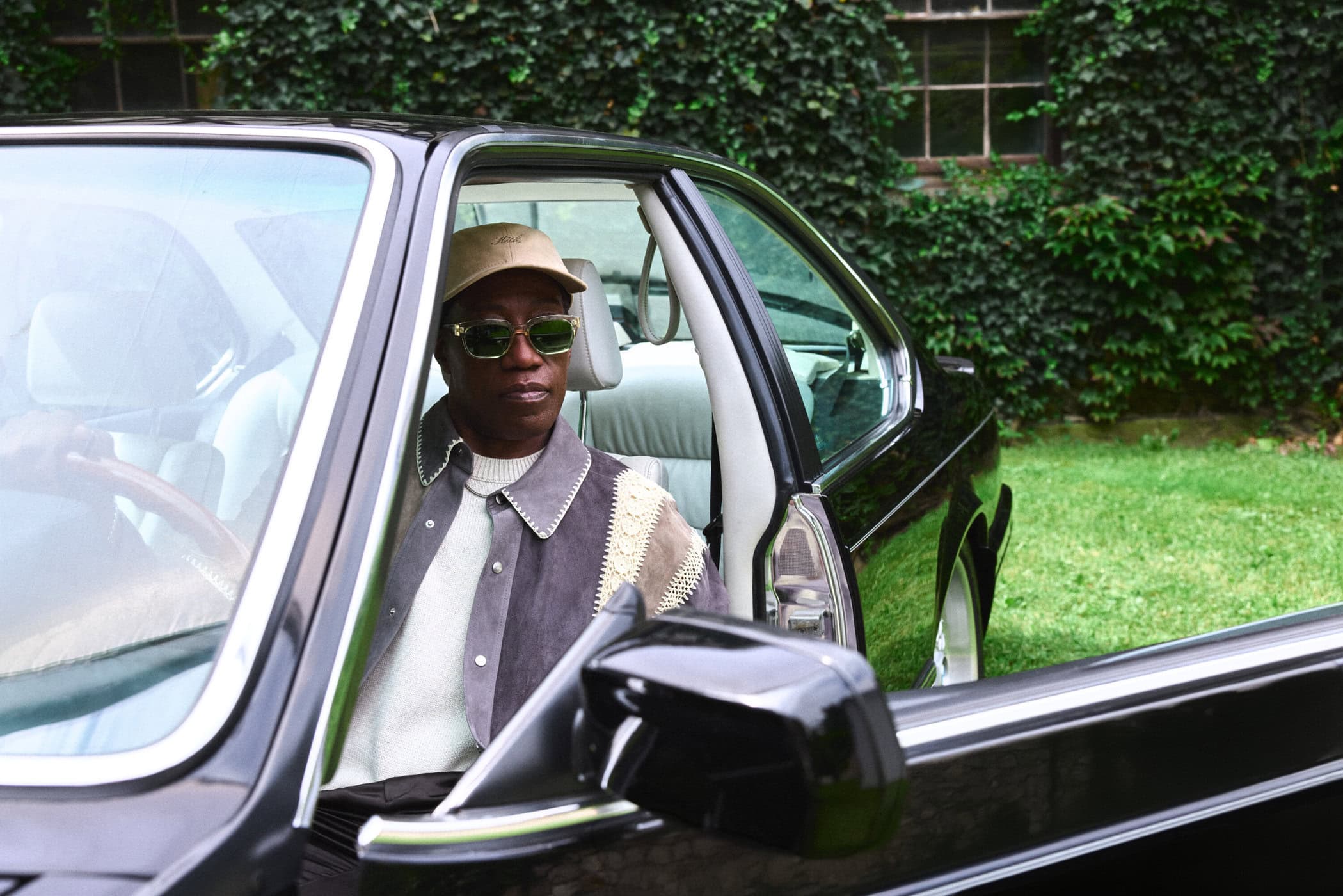 Wesley Snipes wearing sunglasses and a cap seated inside a black car for Kith Fall 2024 campaign