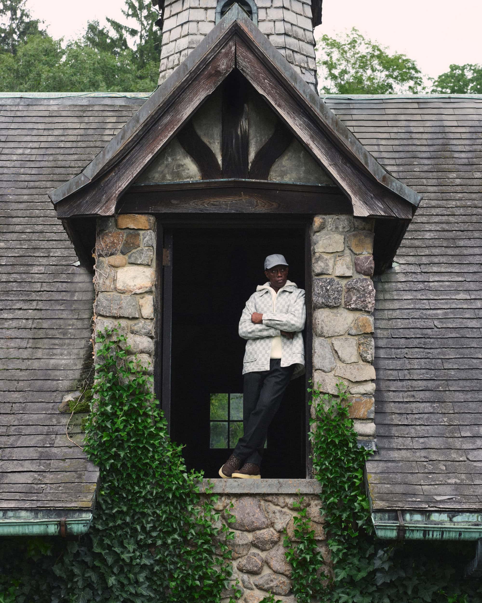 Wesley Snipes leaning in a stone cottage doorway wearing a patterned jacket and cap for Kith Fall 2024