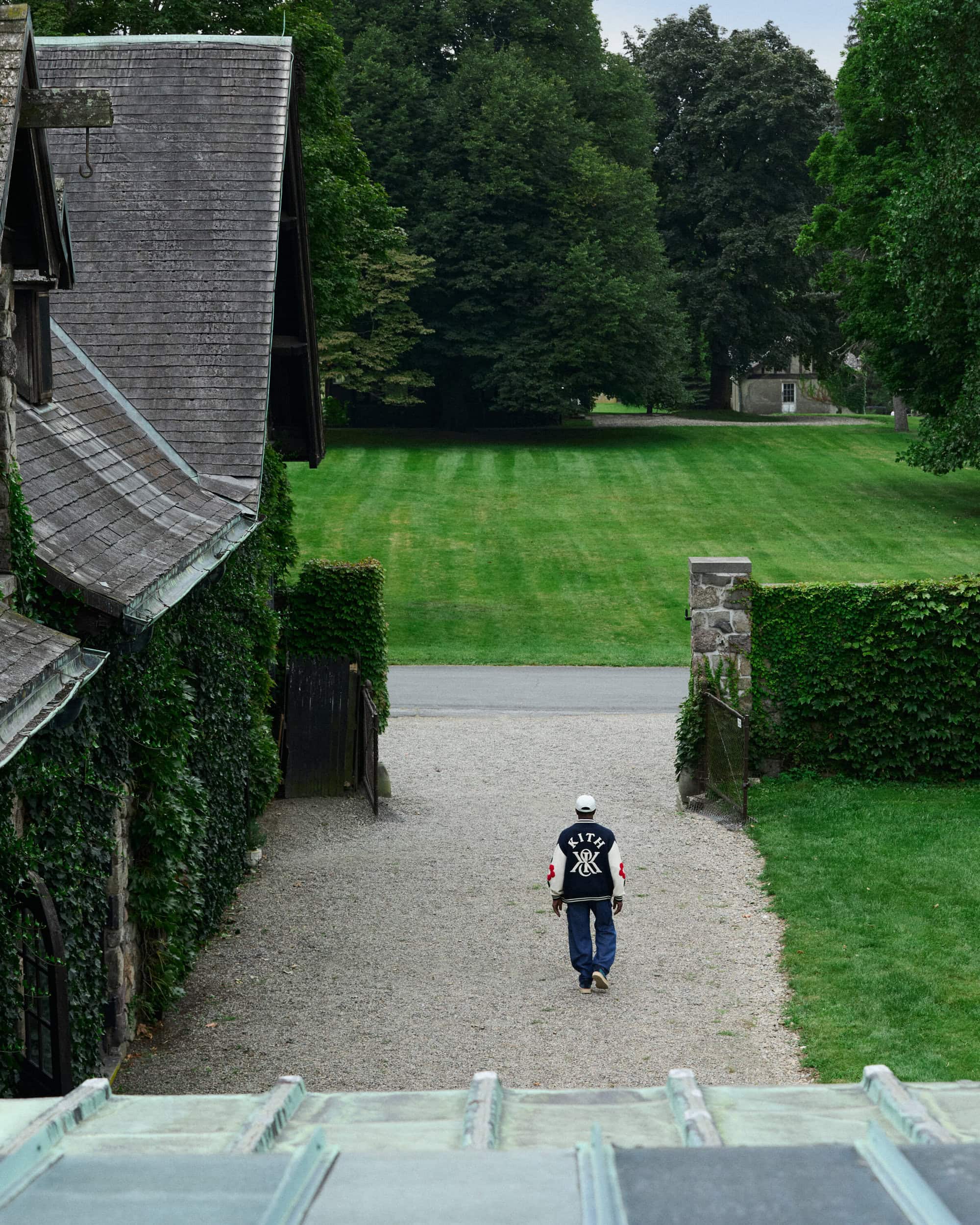 Wesley Snipes walking away down a gravel path between historic estate buildings and manicured lawns for Kith