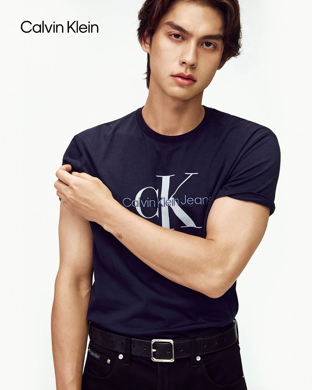 Bright Vachirawit wearing a dark navy Calvin Klein t-shirt against a plain white seamless studio background.