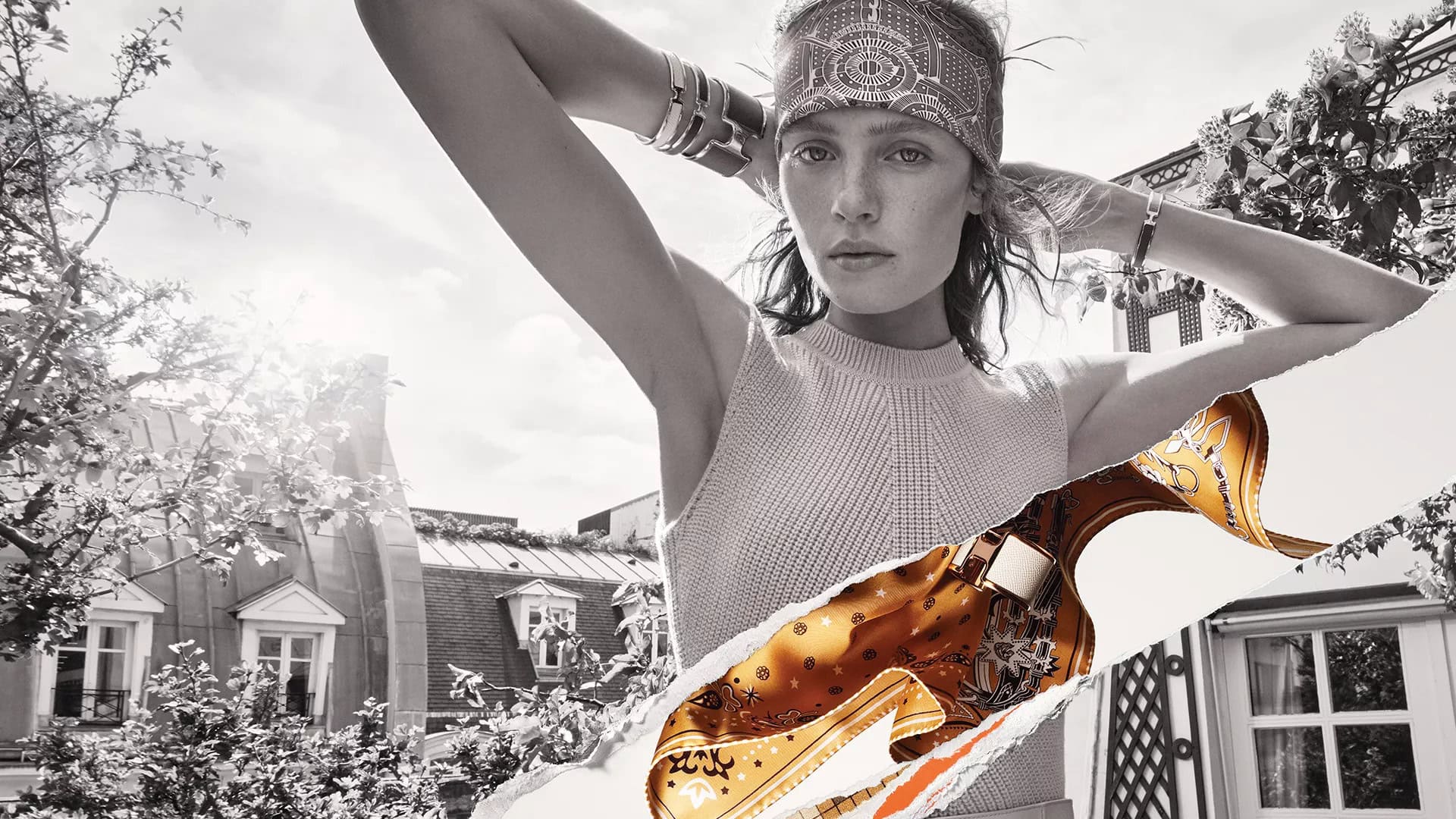 Monochrome fashion campaign image featuring a model wearing a patterned headscarf and bracelets, with a torn paper overlay revealing a gold scarf
