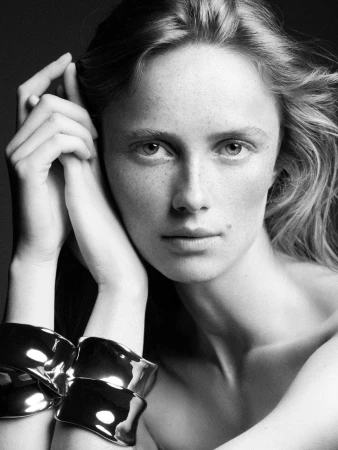 Monochrome portrait of model Rianne Van Rompaey wearing silver cuffs for COS Fall 2024 campaign