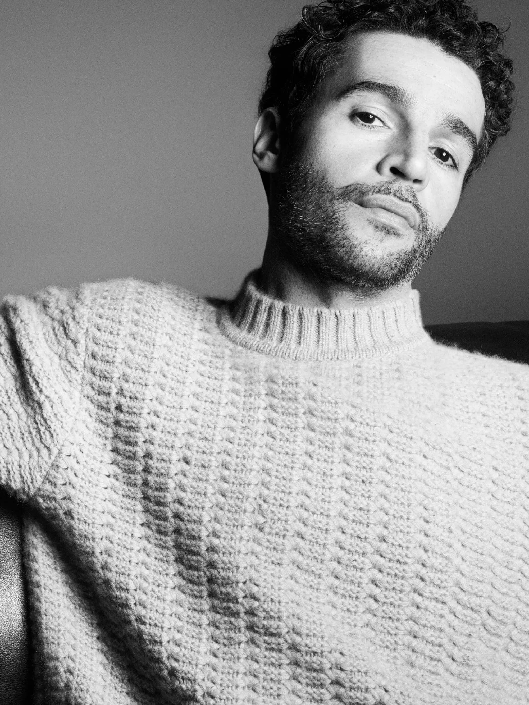 Man wearing a textured knit sweater posing for the COS Fall 2024 campaign, photographed in black and white by Karim Sadli.
