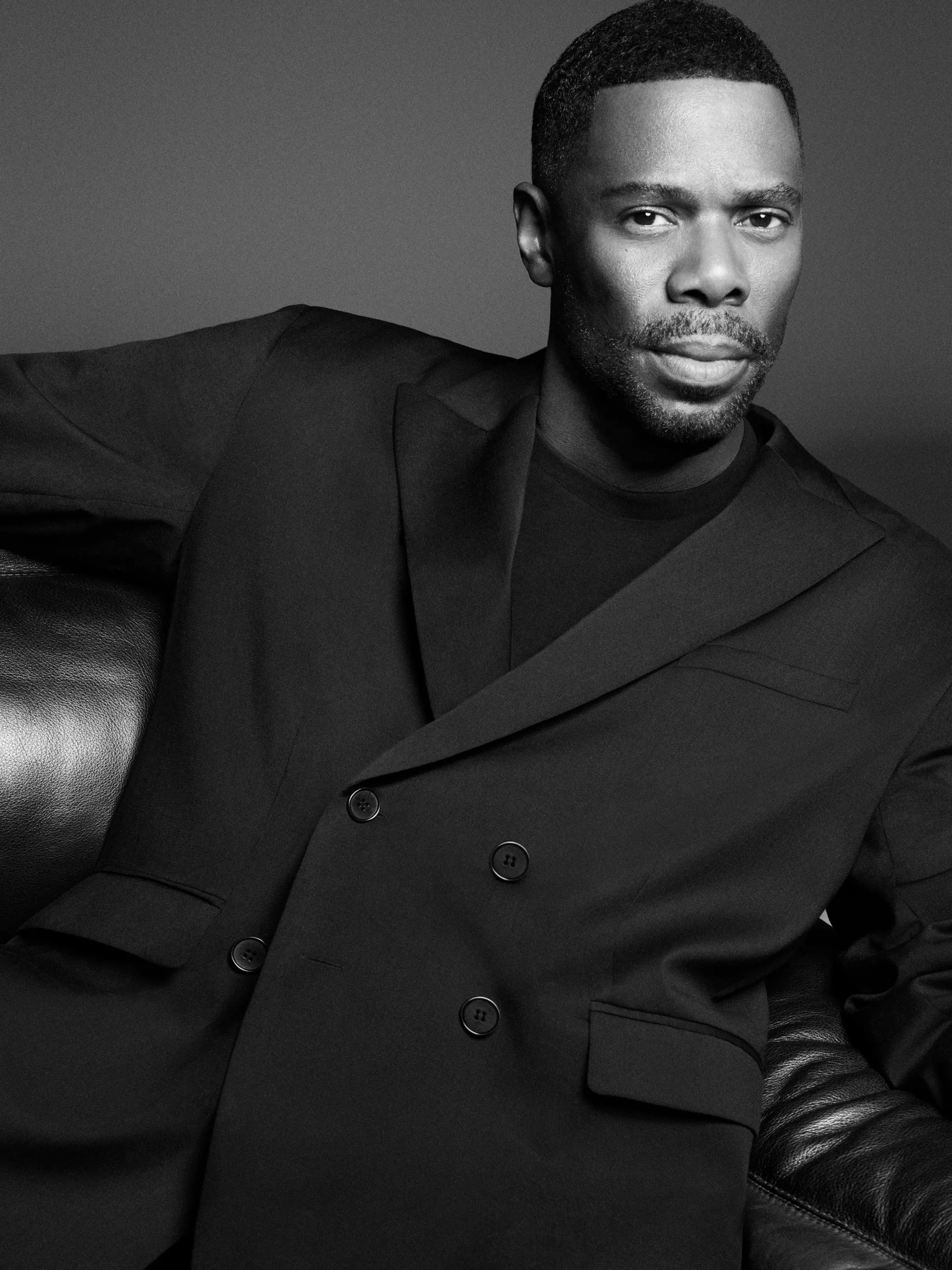 Colman Domingo wearing a black double-breasted suit jacket against a dark studio background for COS
