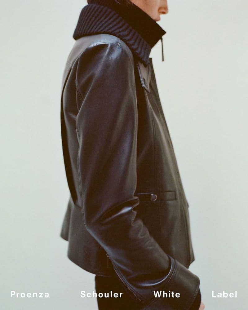 Model wearing a dark leather jacket with a ribbed collar against a pale seamless background for Proenza Schouler