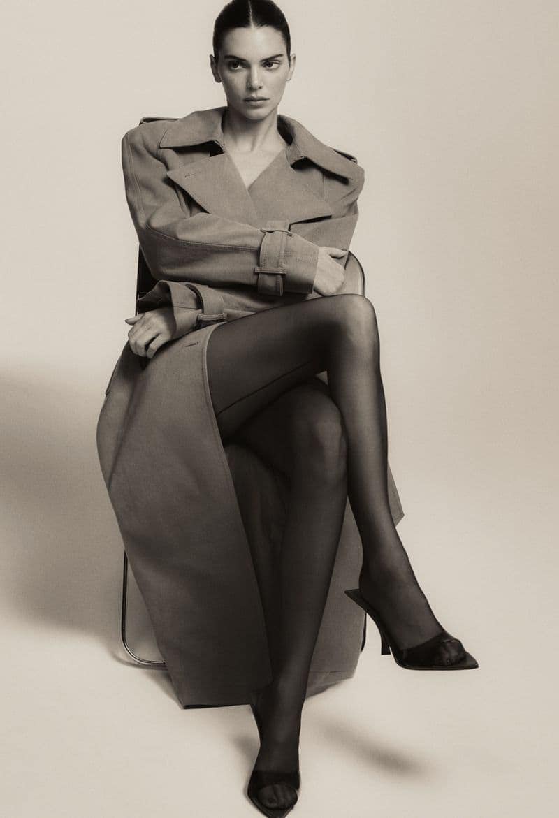 Kendall Jenner seated in a structured coat and black heels against a neutral studio backdrop for FWRD