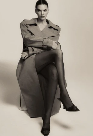 Kendall Jenner seated in a structured coat and black heels against a neutral studio backdrop for FWRD