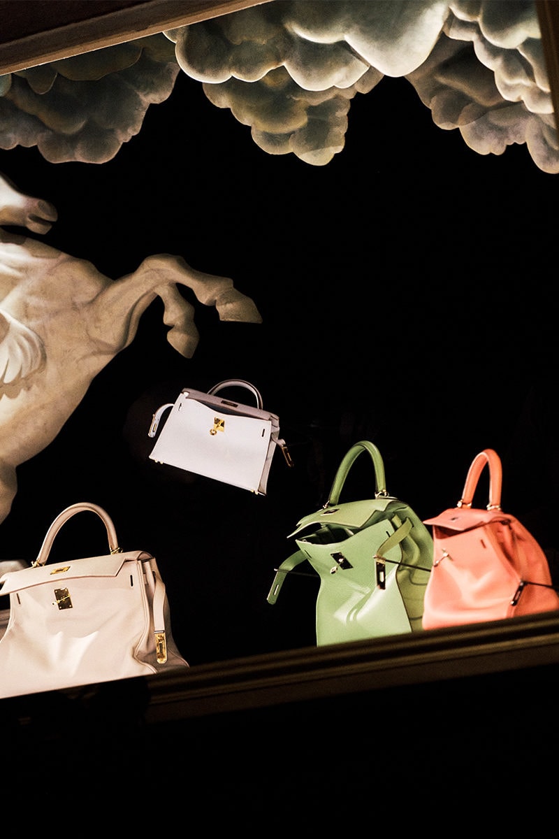 Surreal display with floating leather handbags and sculpted horse against a black backdrop with clouds