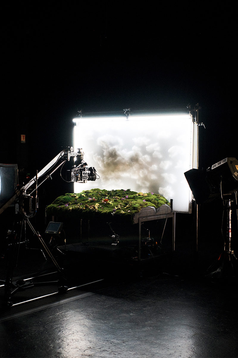 Behind-the-scenes film set featuring a moss-covered table under studio lighting with a camera rig overhead for Hermes.