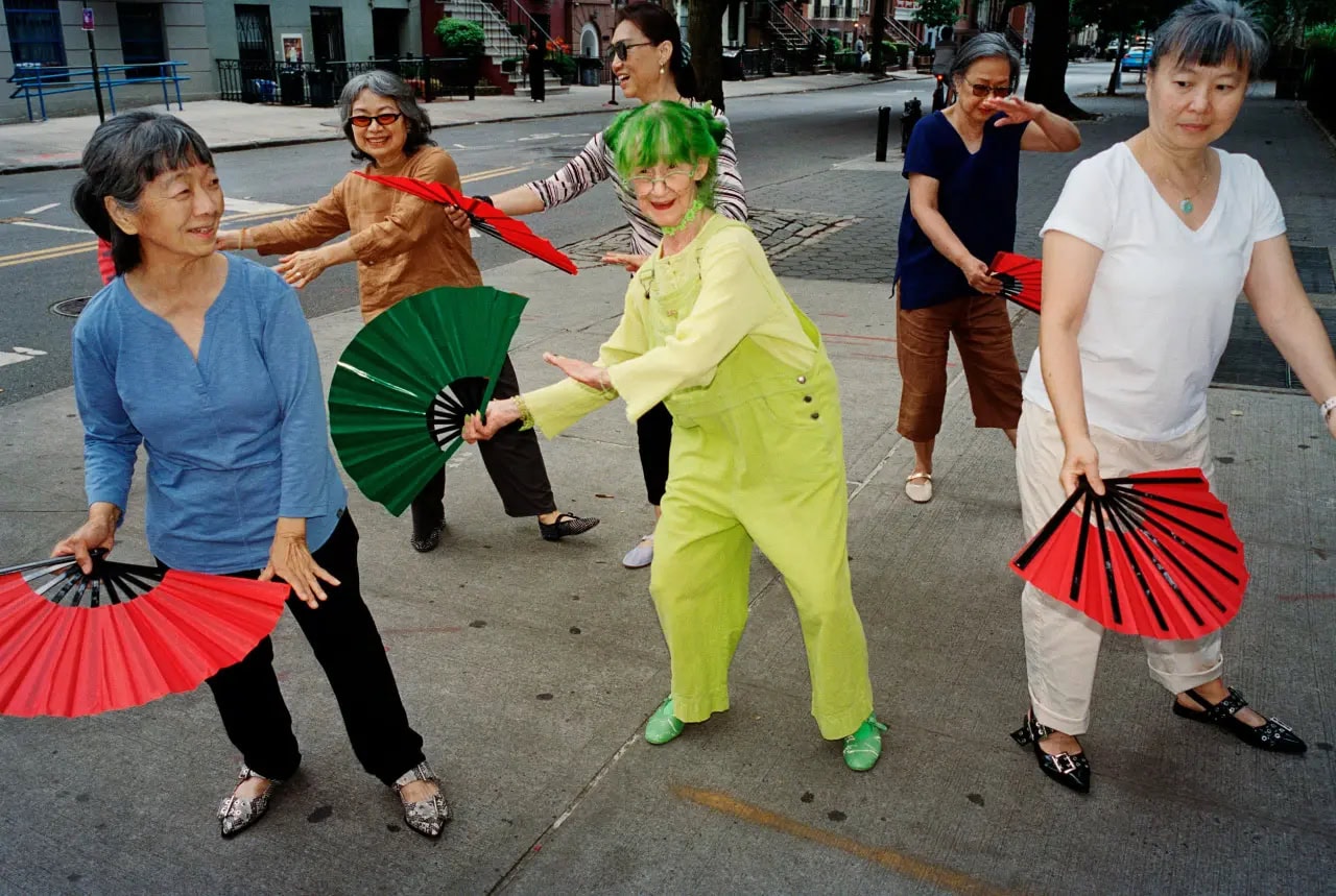 Group of six older women dancing outdoors on a New York City sidewalk holding folding hand fans for Steve Madden Fall 2024 Ad Campaign