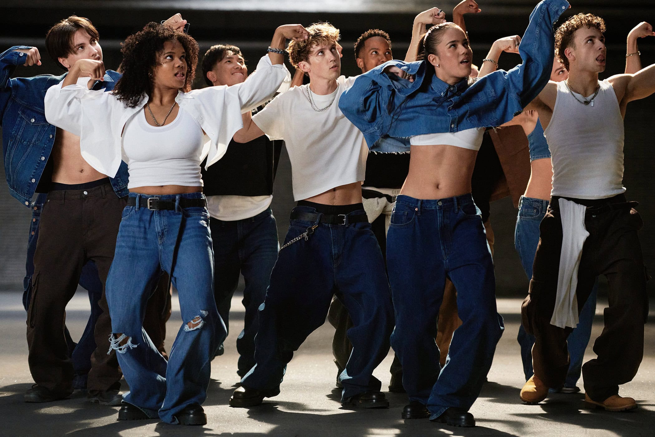 Group of dancers wearing denim and white tops posing dynamically in a concrete street setting for the Gap Fall 2024 ad campaign.