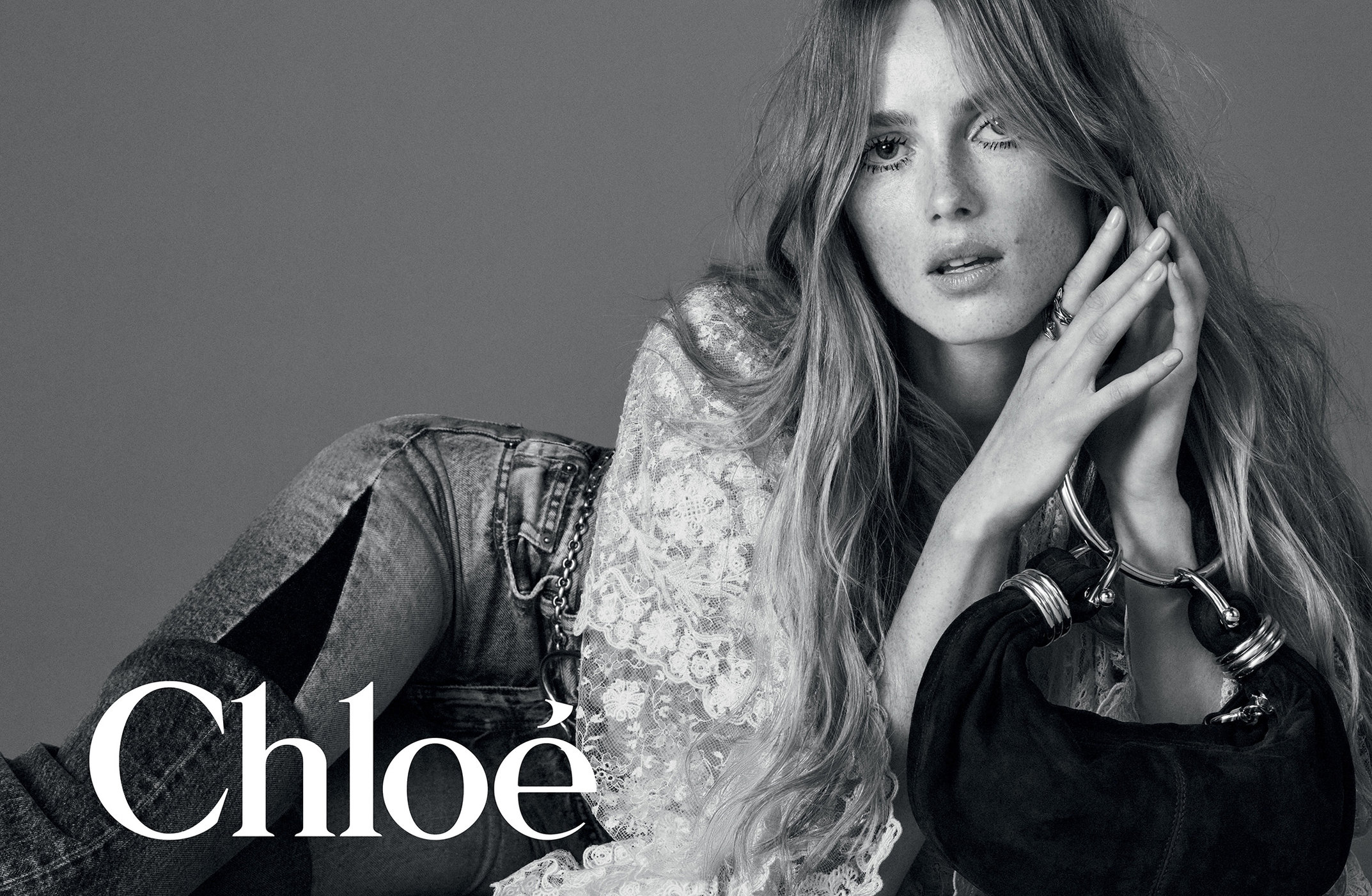 Model in lace top and denim holding a handbag with metal rings for Chloe Winter 2024 ad campaign